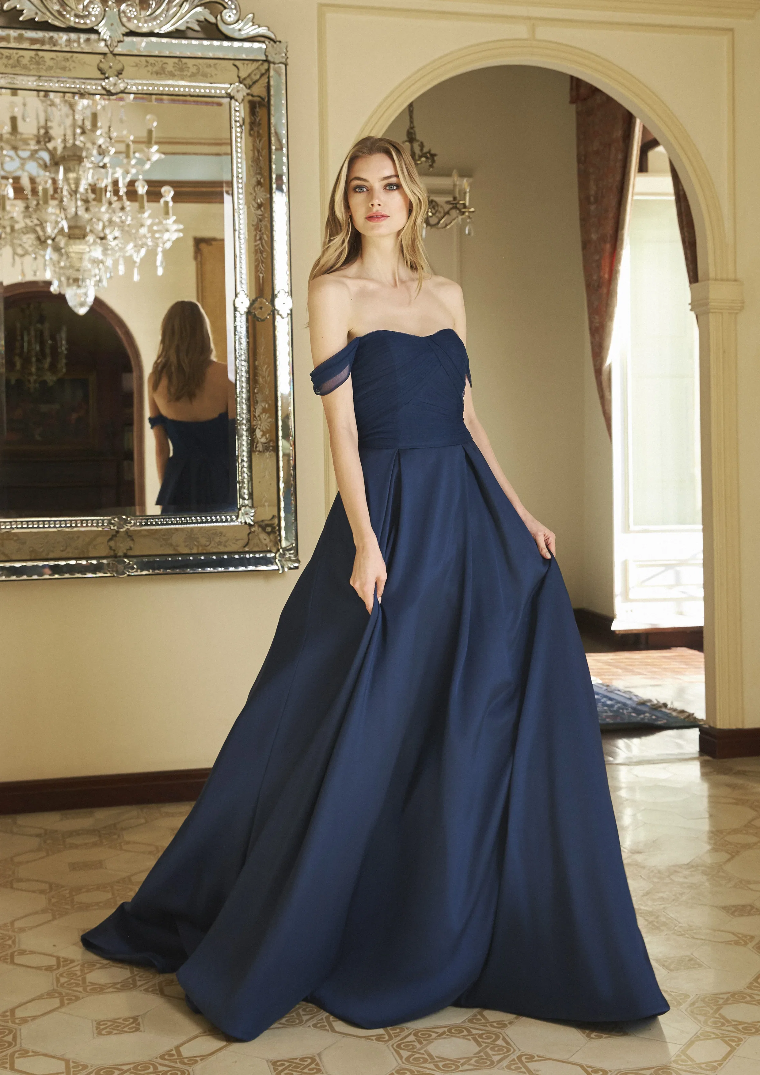 Vrouw in donkerblauwe avondjurk met off the shoulder mouwtjes