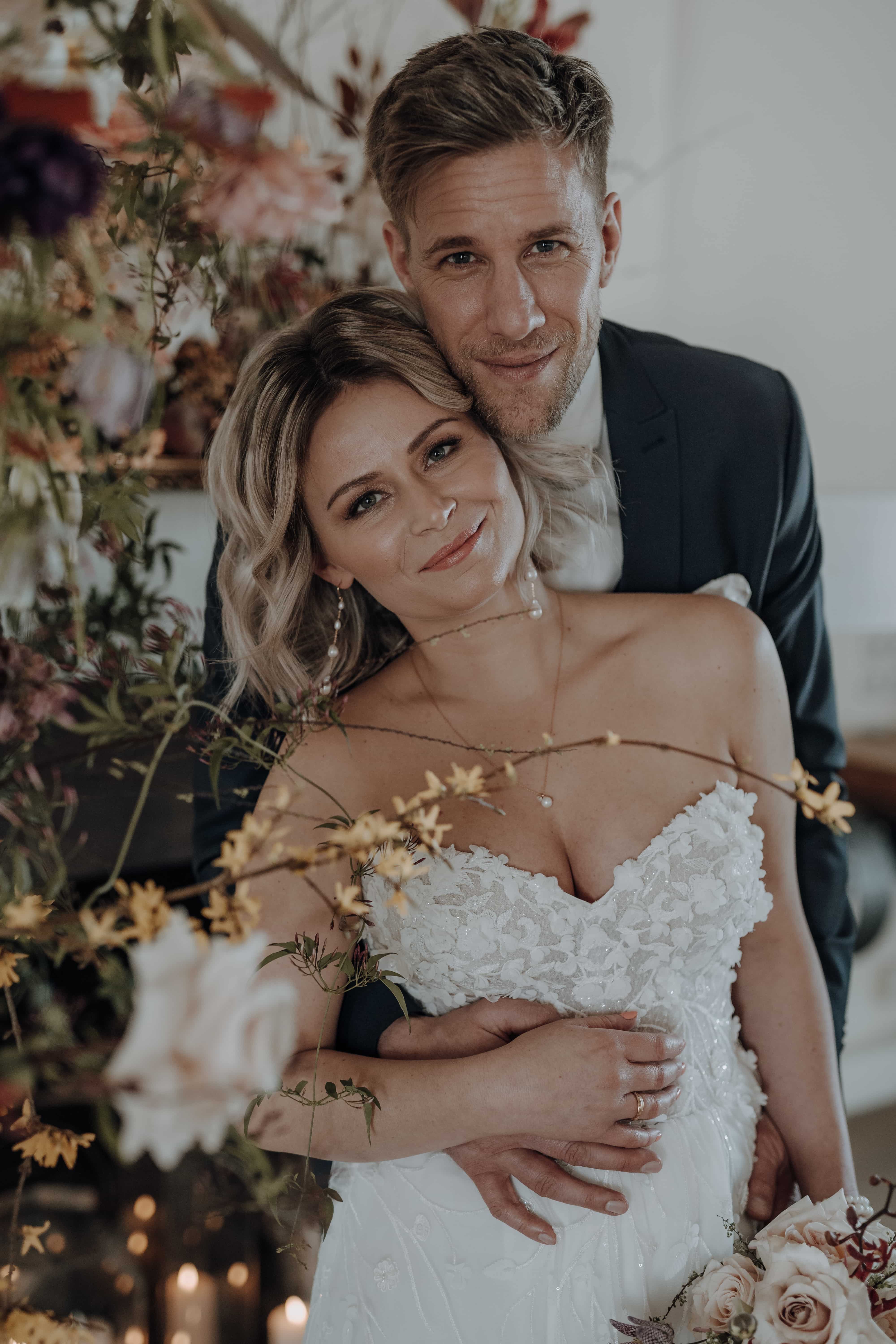 Bruidspaar kijkt vrolijk in de camera.