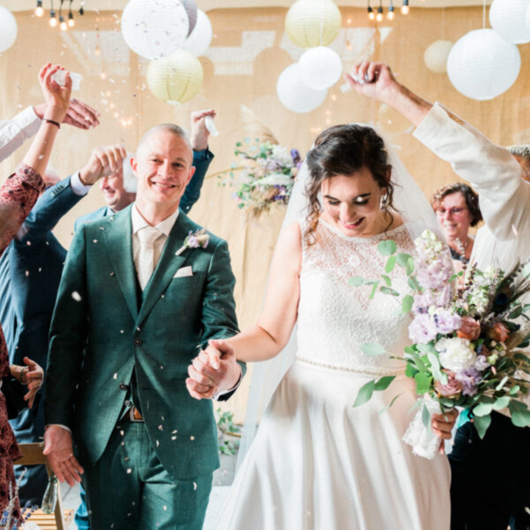 Vrolijk bruidspaar loopt hand in hand van het altaar weg terwijl familie en vrienden confetti gooien.