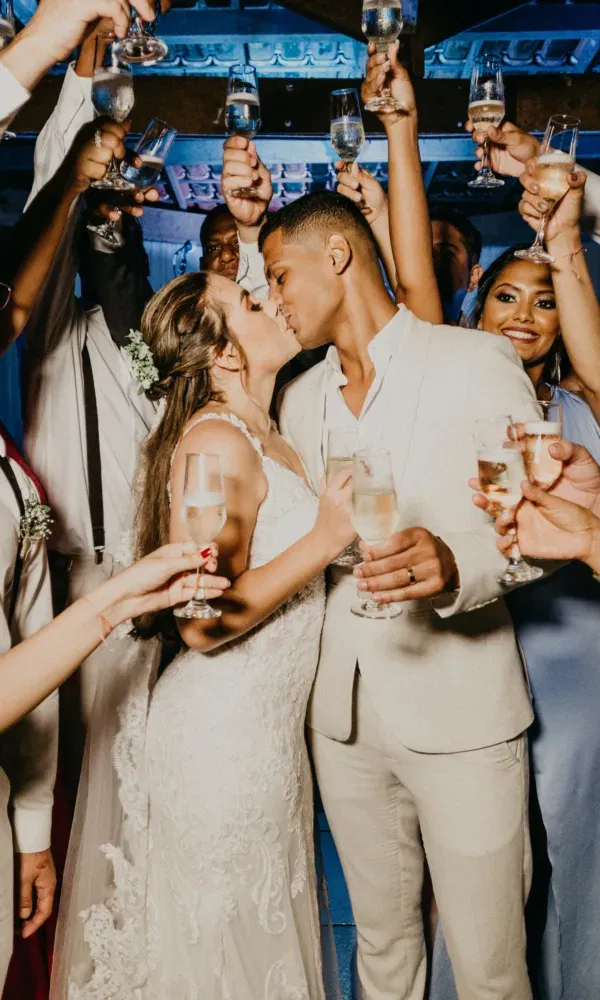 Bruidspaar staat tussen wedding gasten met champange en zoenen