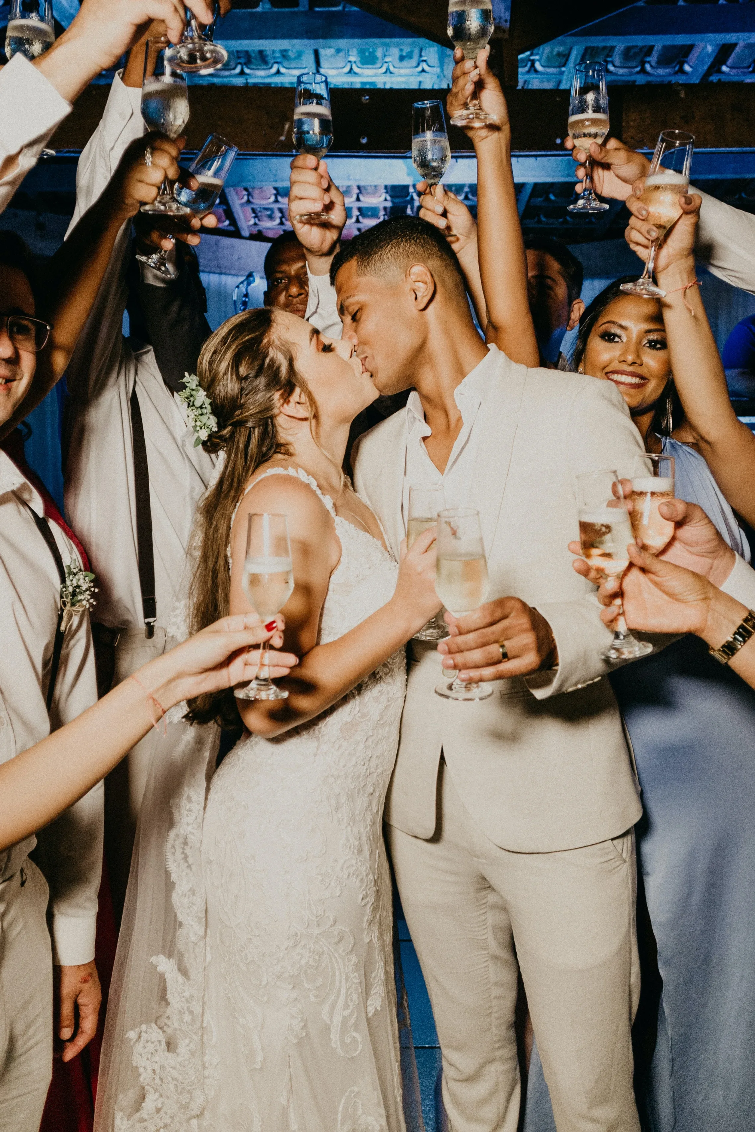 Bruidspaar staat tussen wedding gasten met champange en zoenen