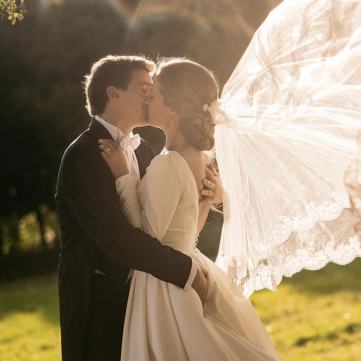 Bruidspaar dat kust, sluier waait in de wind.