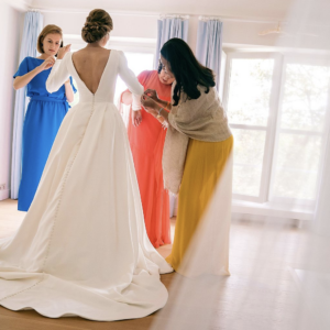 Bruid die met de hulp van vriendinnen haar jurk aantrekt.