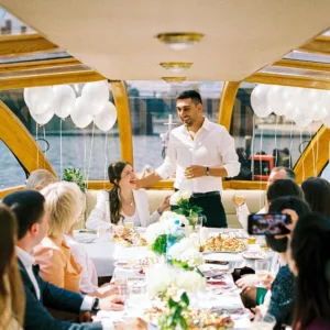 Stel op boot tijdens etentje, man geeft speech