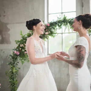 Twee trouwende vrouwen bij bruidstaart voor bloemenboog.