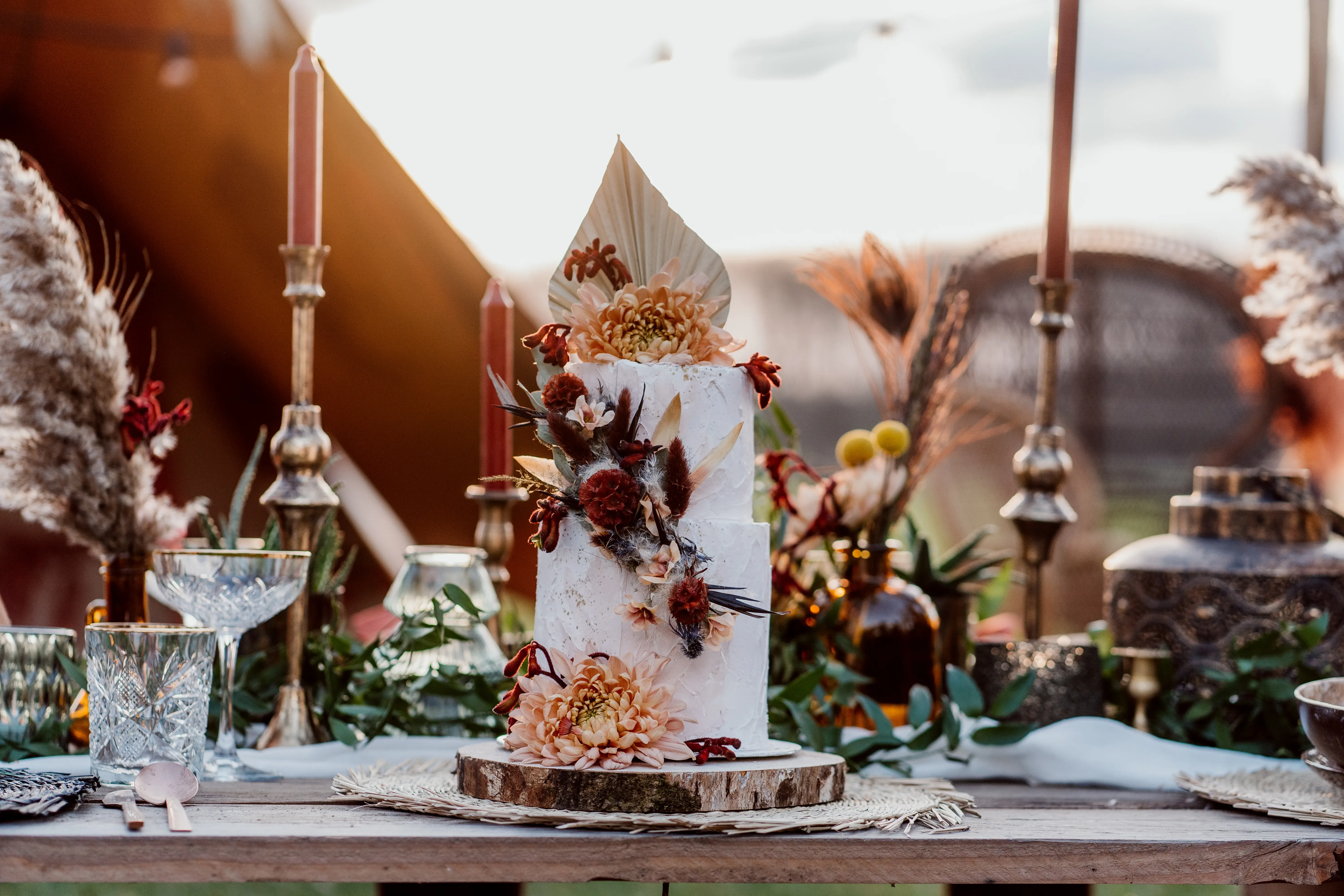 Boho bruidstaart op tafel bij ondergaande zon tijdens golden hour.