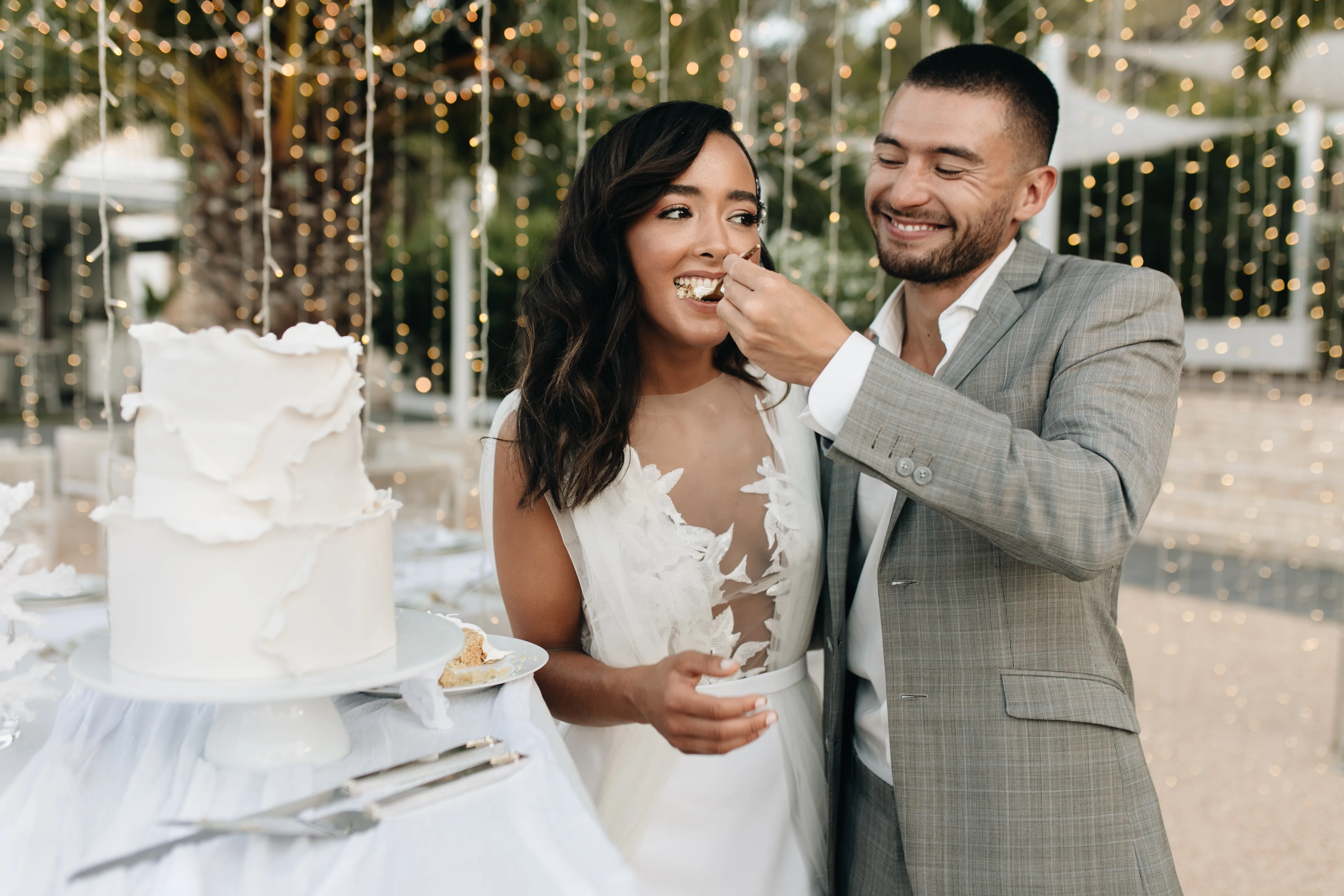Bruid en bruidegom eten bruidstaart, man voert vrouw taart.