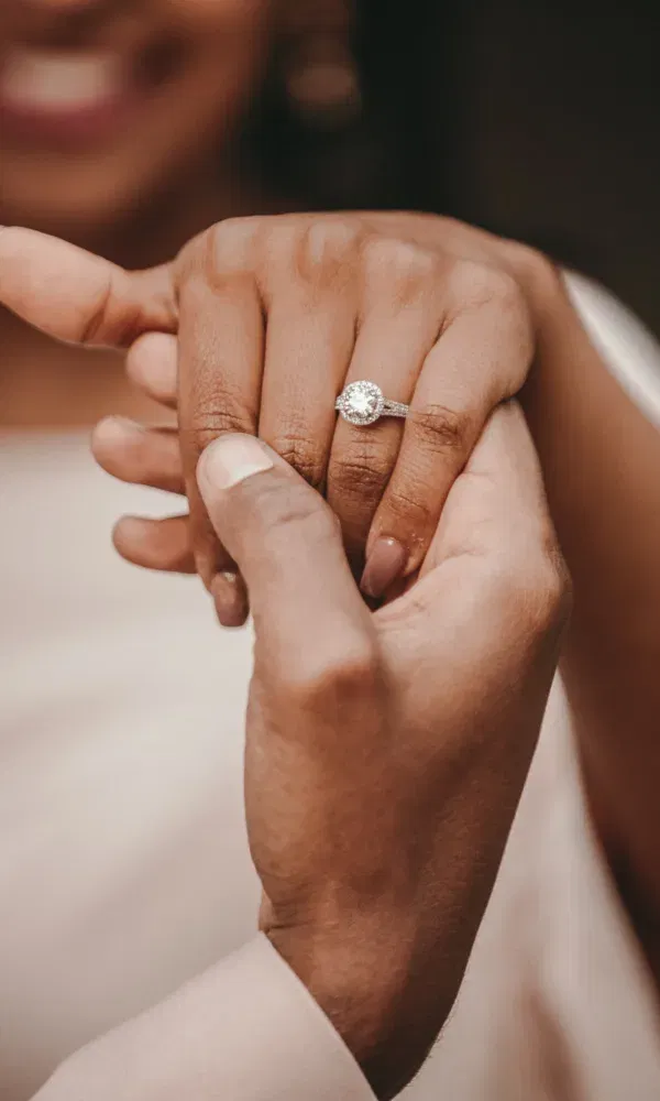 Vrouw met verlovingsring aan hand, die wordt vastgehouden door man.