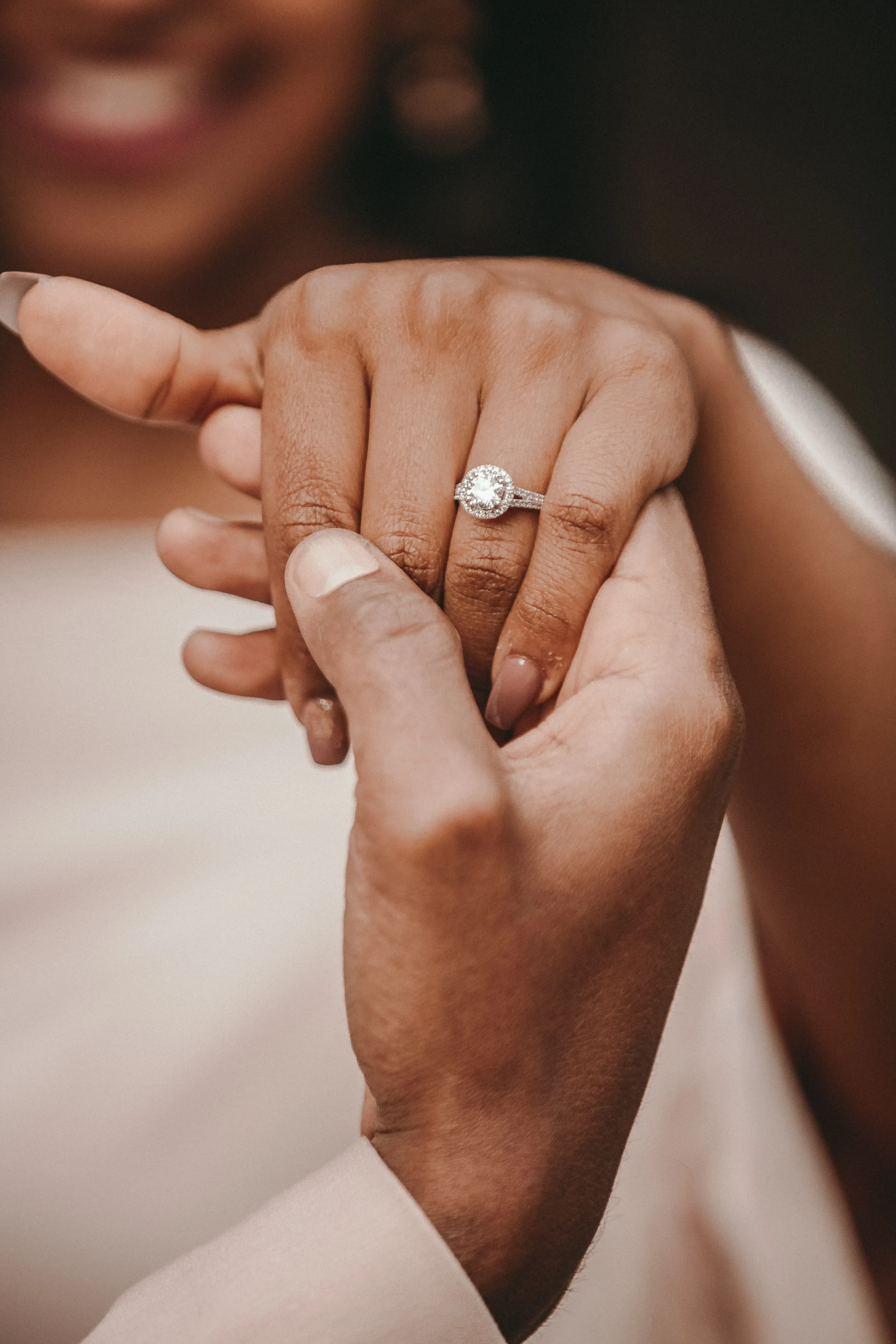 Vrouw met verlovingsring aan hand, die wordt vastgehouden door man.