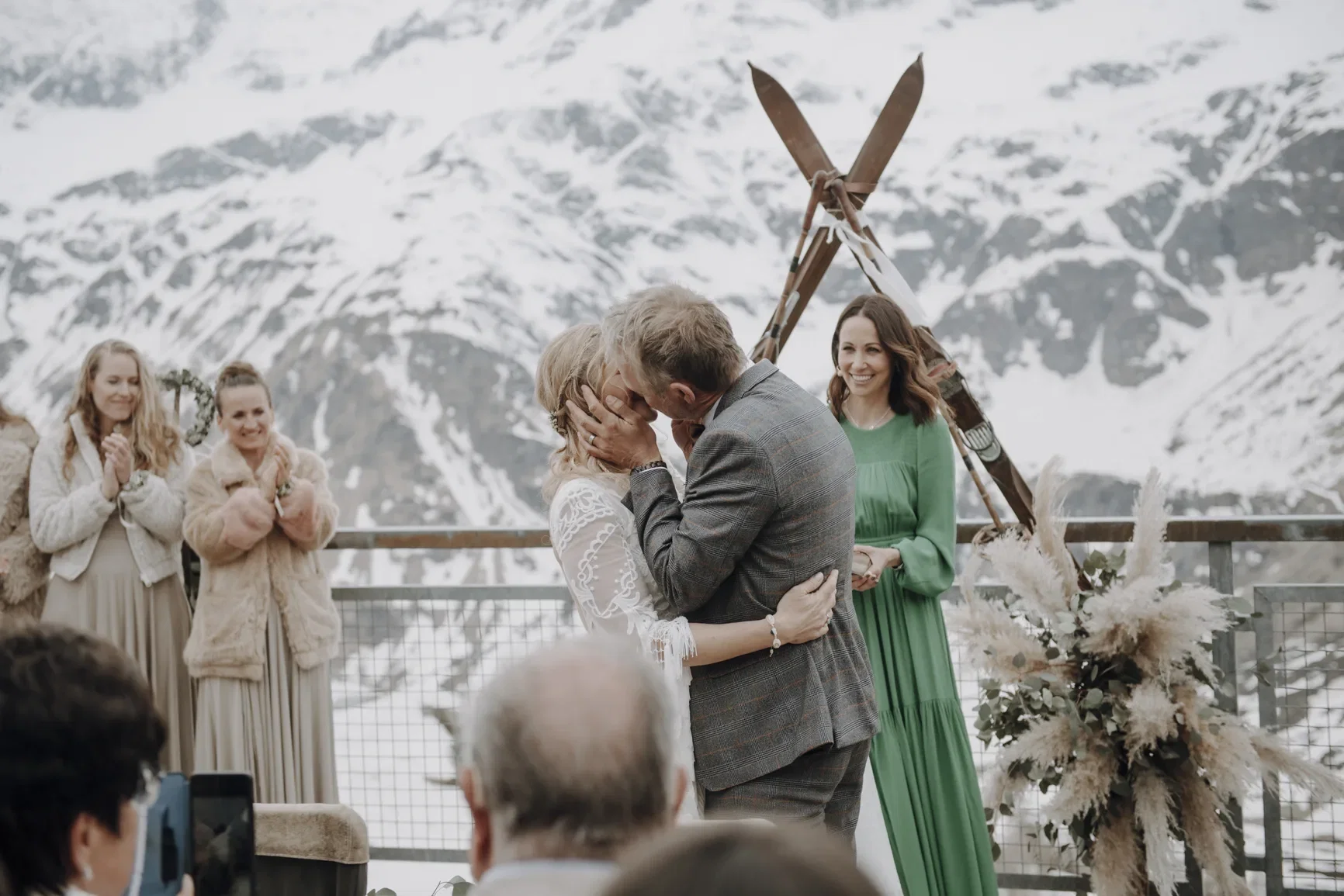 Bruidspaar kust tijdens ceremonie voor besneeuwde bergen.