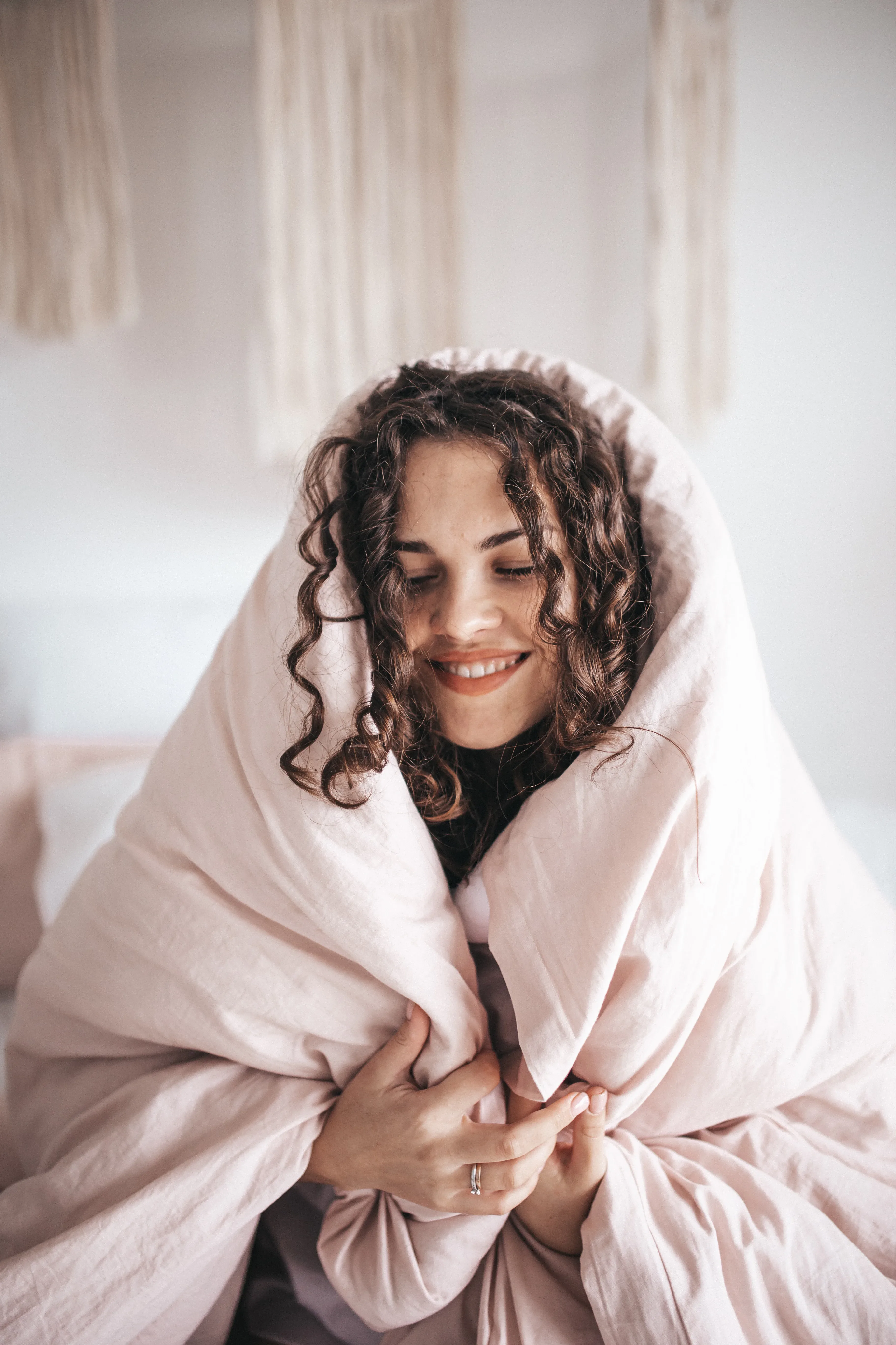 Vrouw kruipt onder roze dekbed en geniet van de ontspanning.