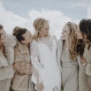 Bruid staat tussen haar bruidsmeisjes in de sneeuw.