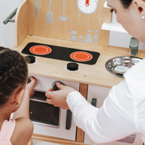 Bruiloft nanny spelend met mini keukentje en kind.