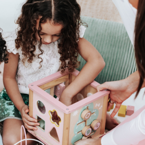 De Bruiloft Nanny aan het werk. Vrouw met twee kinderen en puzzeldoos met blokken op de grond.