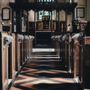 Gangpad in een kerk naar het altaar, langs de kerkbanken hangen bloemen, 