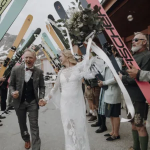 Bruidspaar loopt tussen gasten door, gasten staan met snowboards in de lucht, 