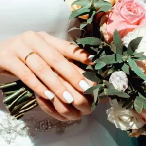 Bruid met trouwring, witte nagels en boeket