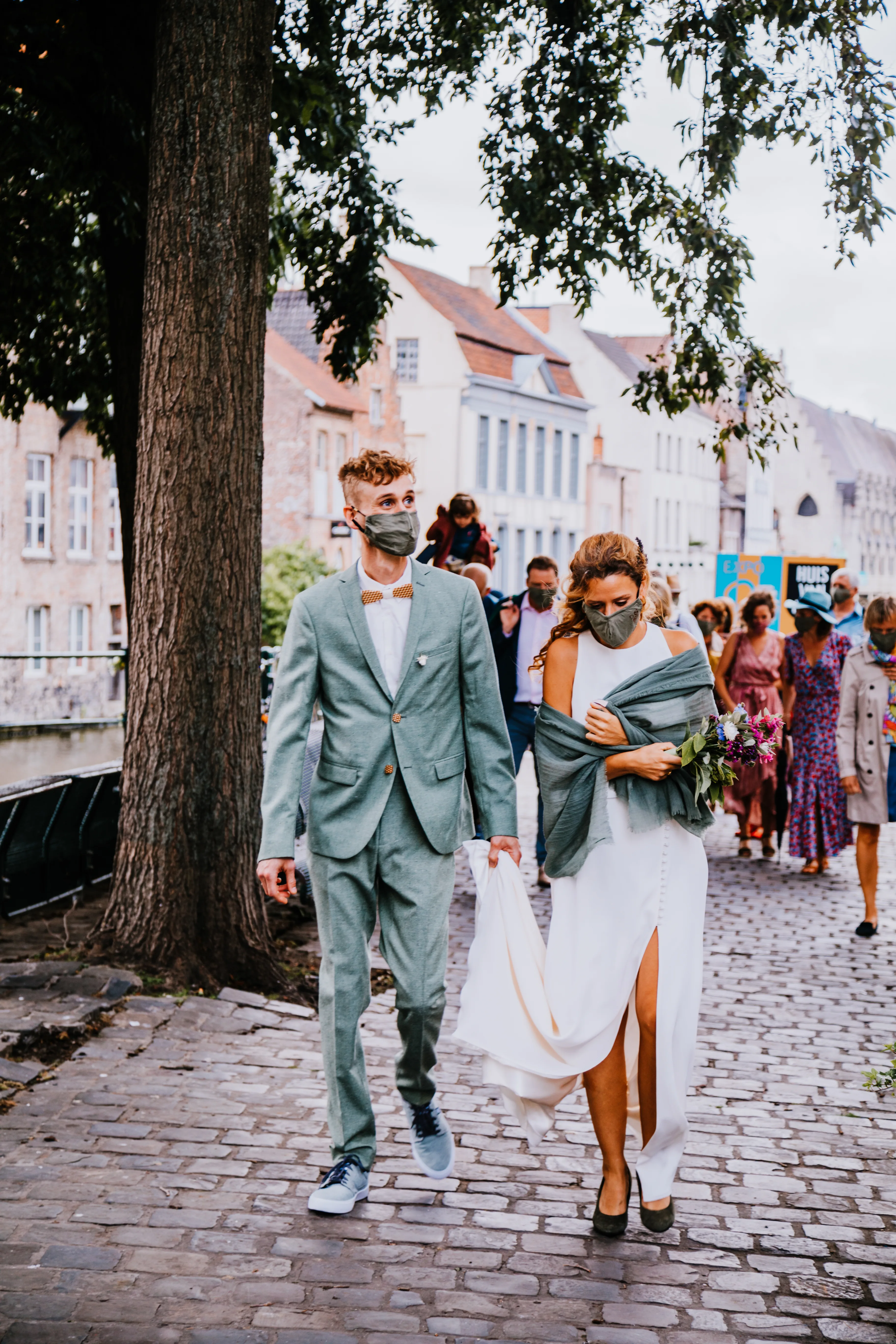 Een bruidspaar met hun familie en vrienden met mondkapjes op