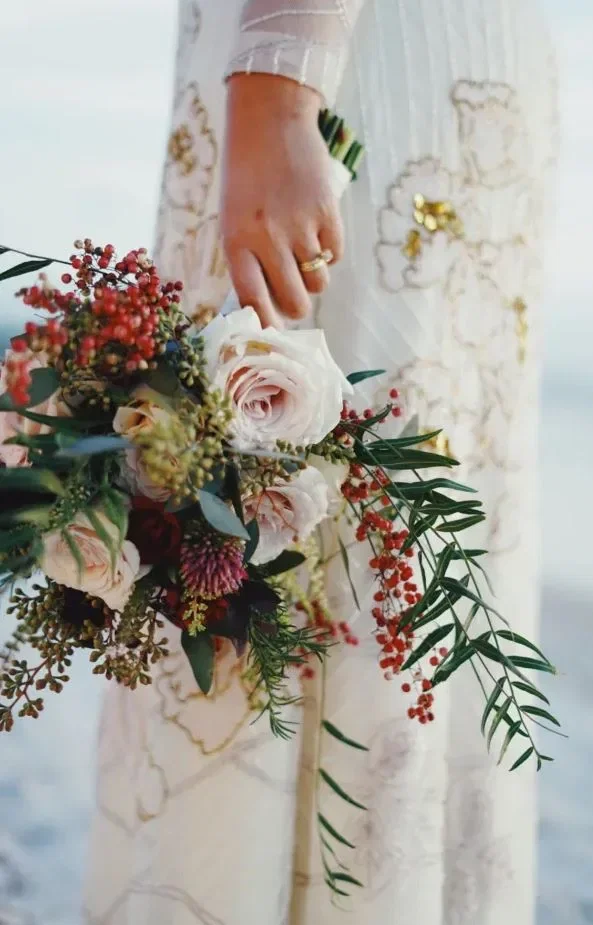 Handen van de bruid houden een bruidsboeket vast.