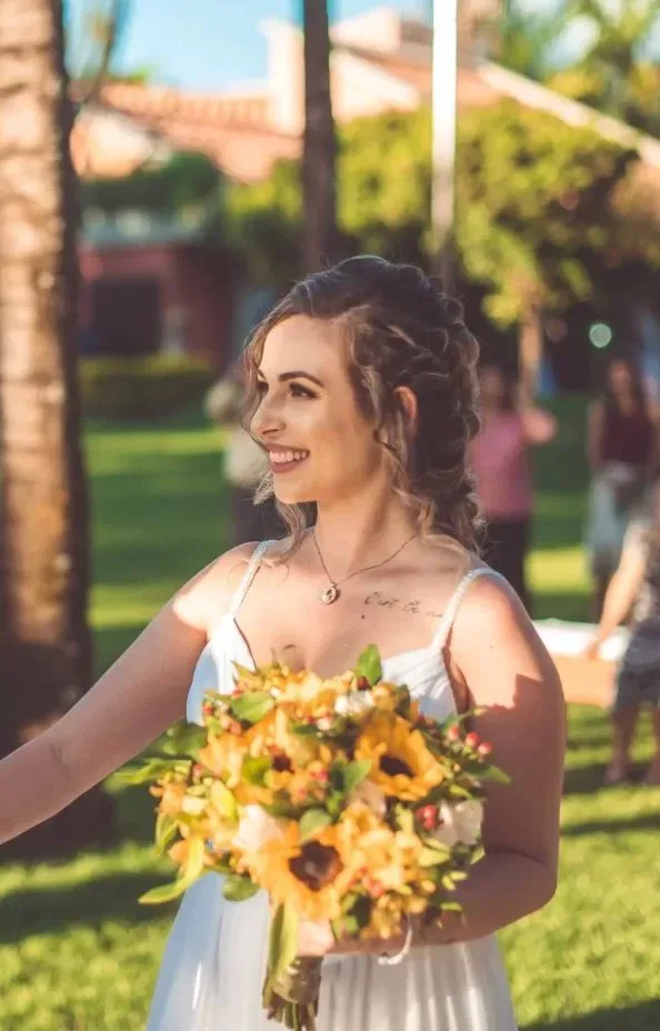 Bruid houdt een met zonnebloemen gevuld bruidsboeket vast in de tuin