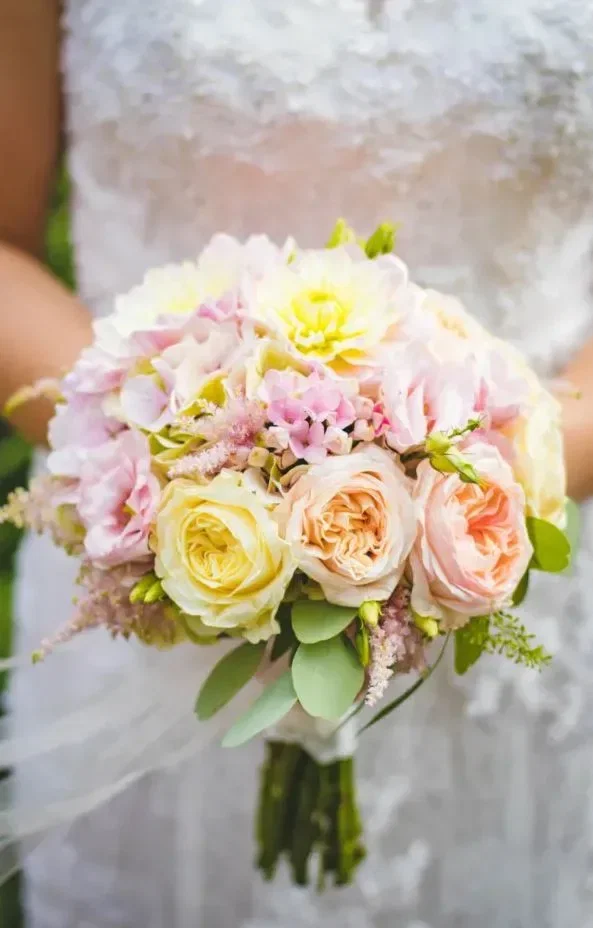 Bruid houdt een klein bruidsboeket vast van verschillende klaprozen