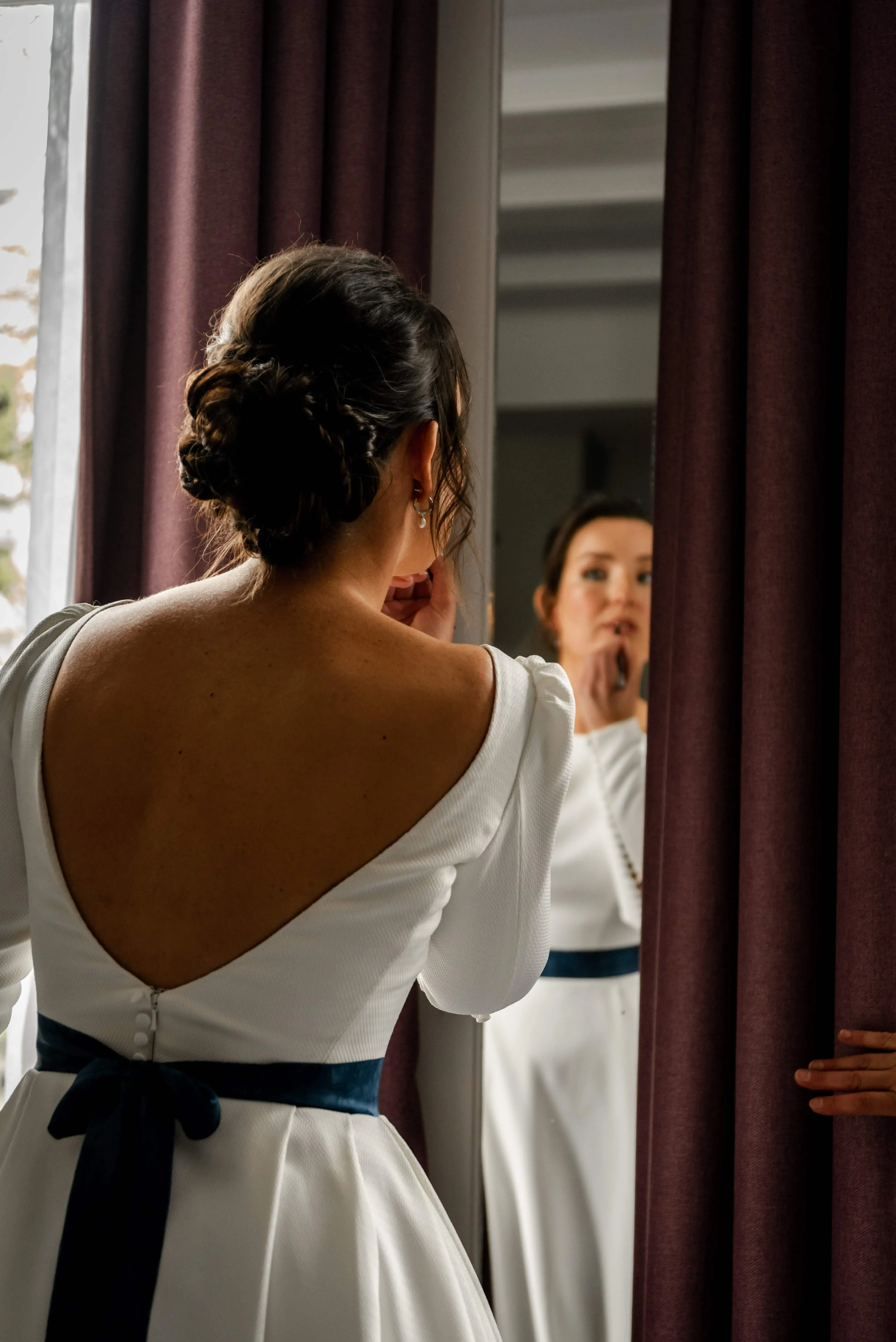 Bruid die make-up doet in de spiegel.