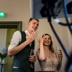Bruidspaar dat trots hun ringen laat zien aan familie via videobellen.