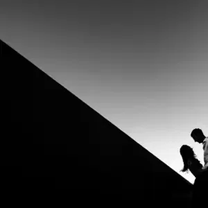 Zwartwit foto van een stel dat buiten staat met een hoog flatgebouw op de achtergrond.