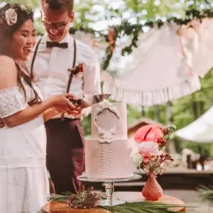 Bruidspaar die hun witte bruidstaart aansnijden