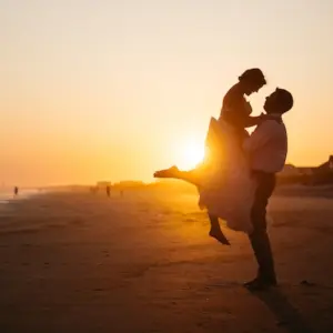 Vrolijk koppel met zonsondergang op het strand