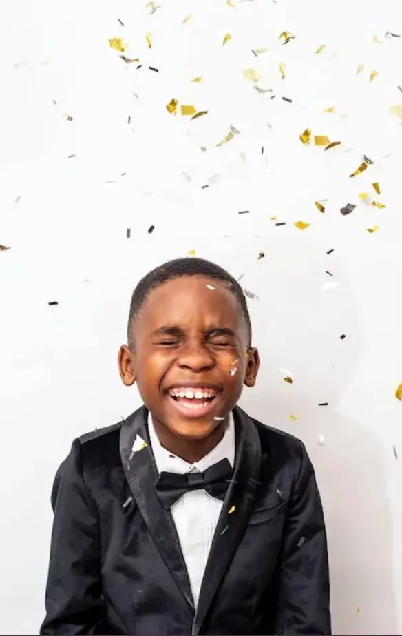 Jongetje in net pak met strik en gouden confetti.