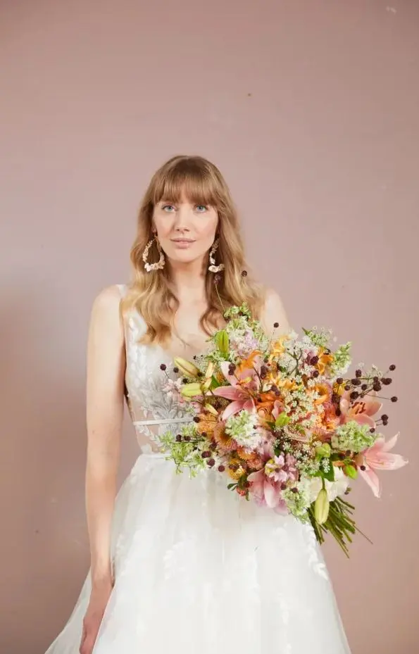 Bruid met witte jurk, bruidsboeket en grote schelp oorbellen