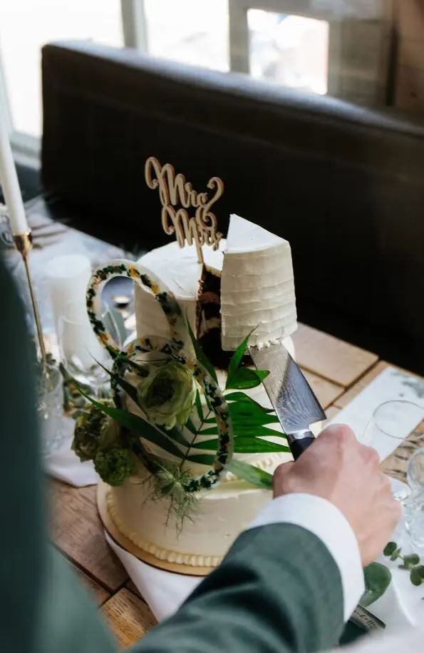 Bruidstaart die wordt aangesneden door de bruidegom