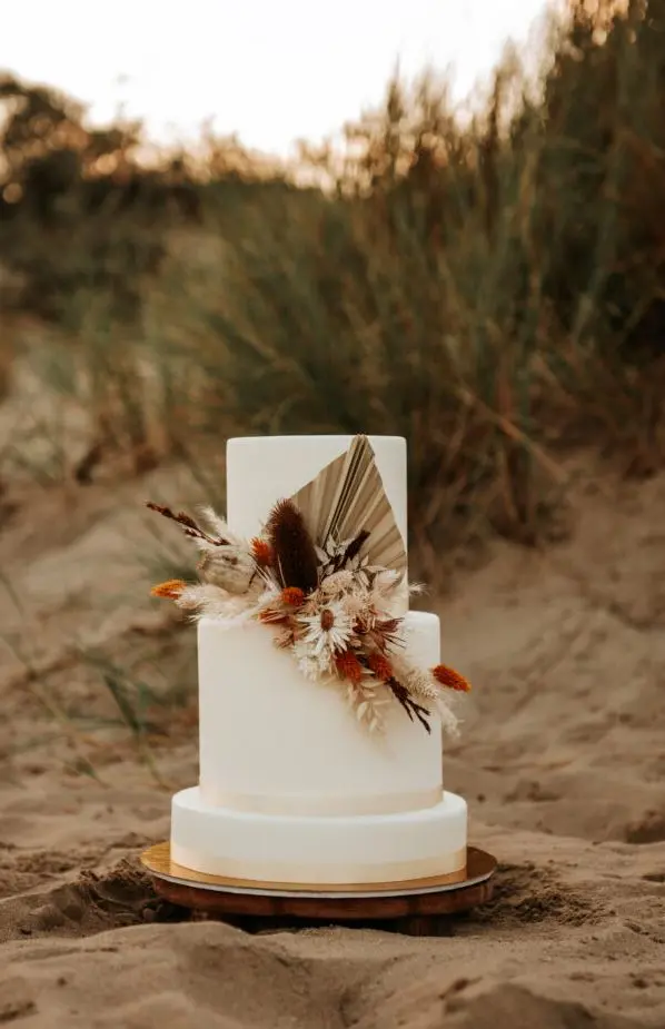 Witte bruidstaart met droogbloemen versiering in de duinen