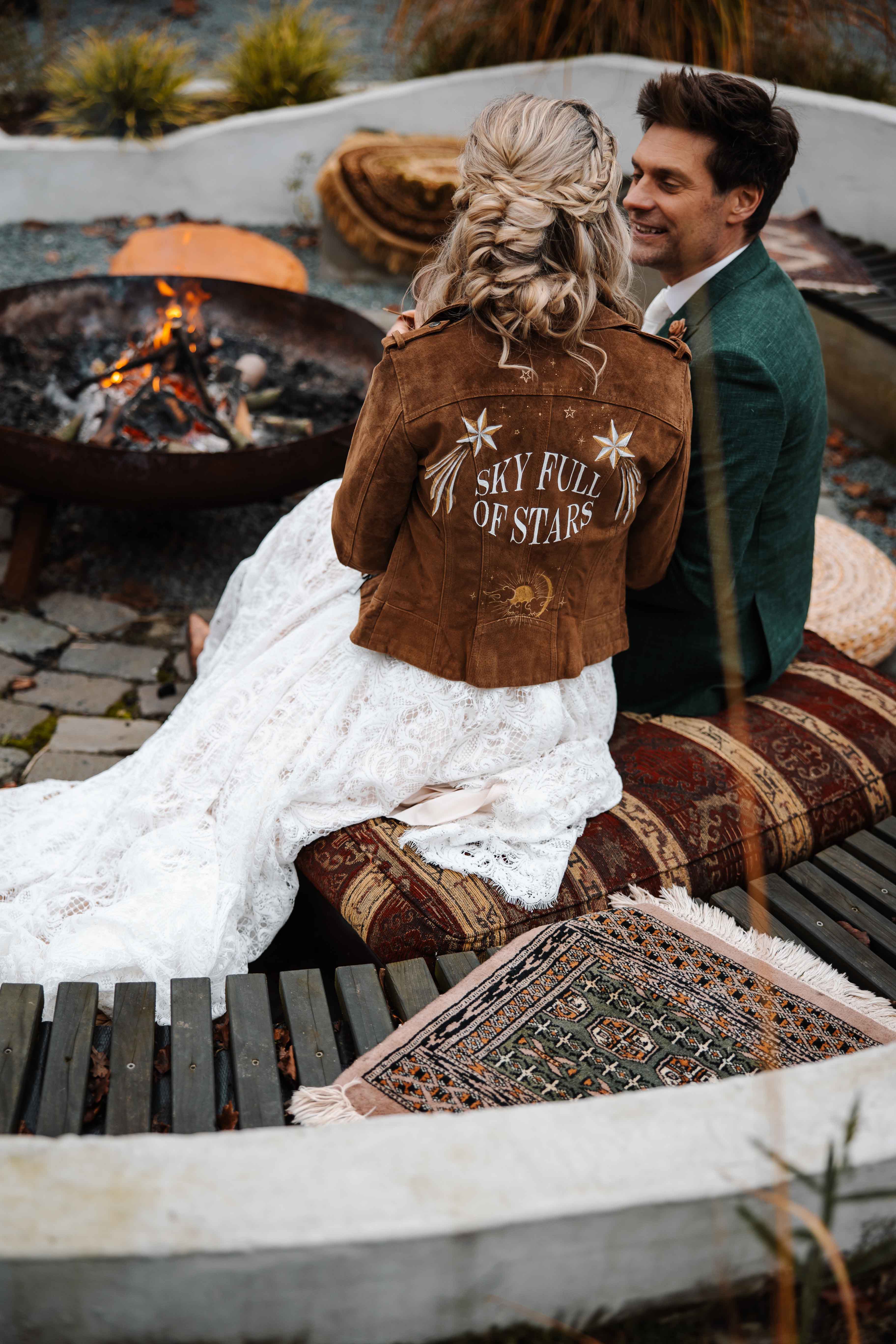 Bruidspaar bij kampvuur. Bruid draagt beschilderd jasje.