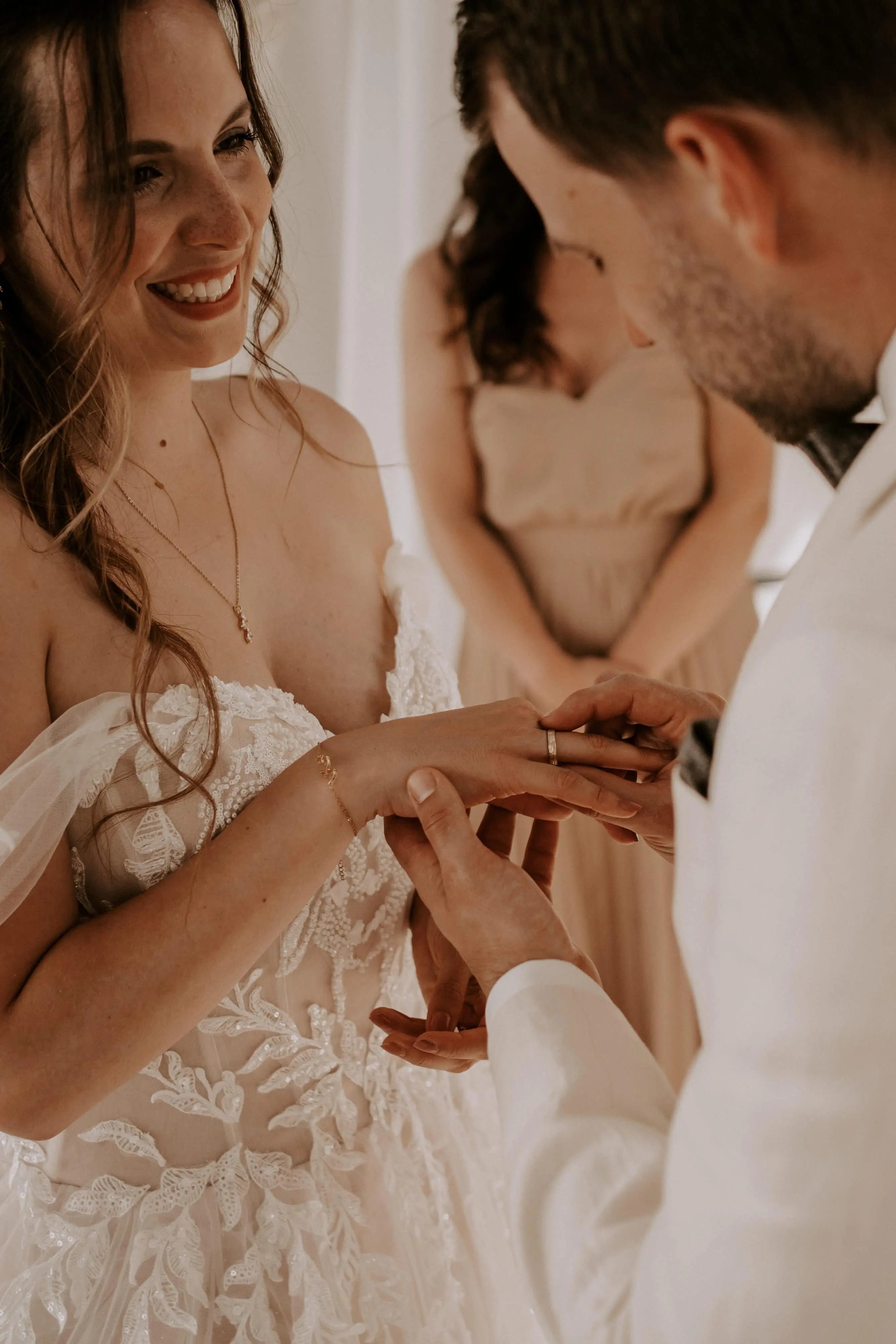 bruidegom schuift trouwring om ringvinger bruid.