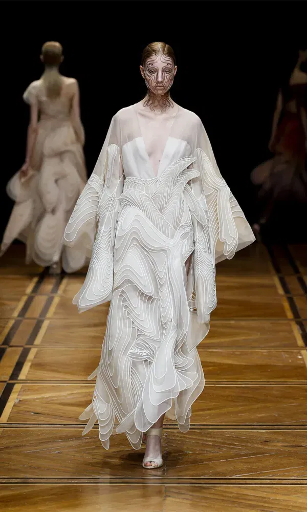 Model in bruidsjurk loopt over catwalk.