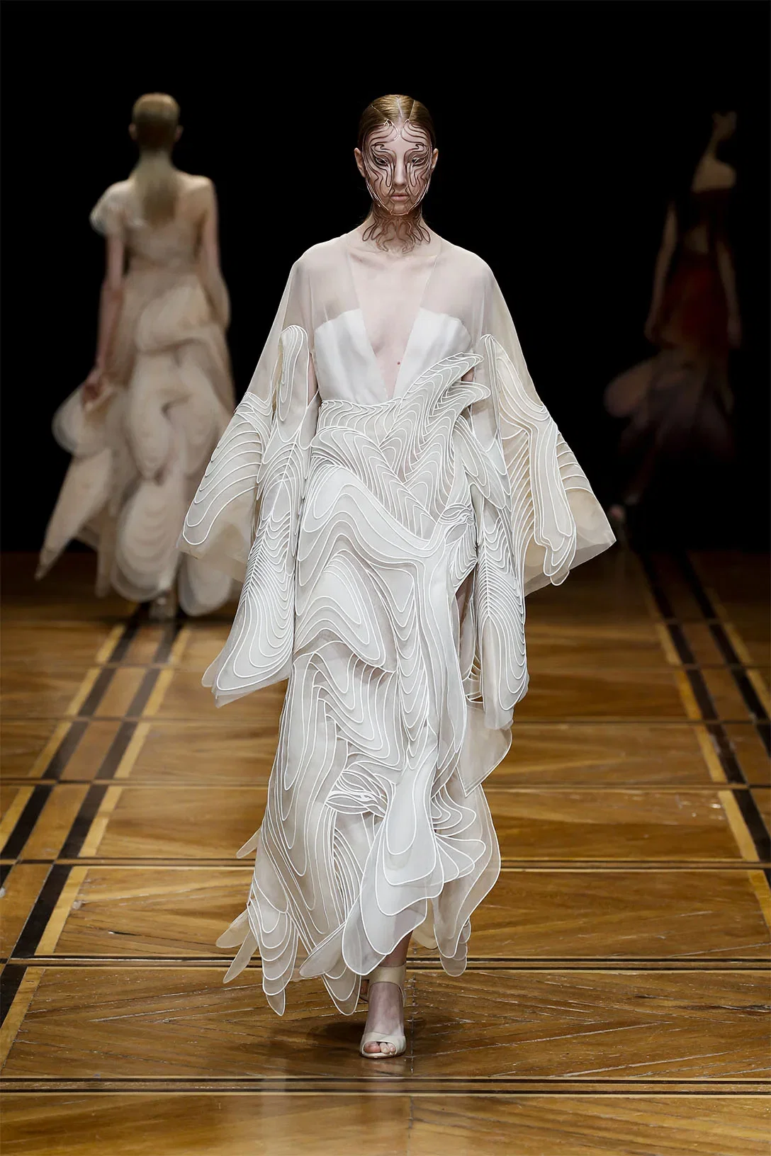 Model in bruidsjurk loopt over catwalk.