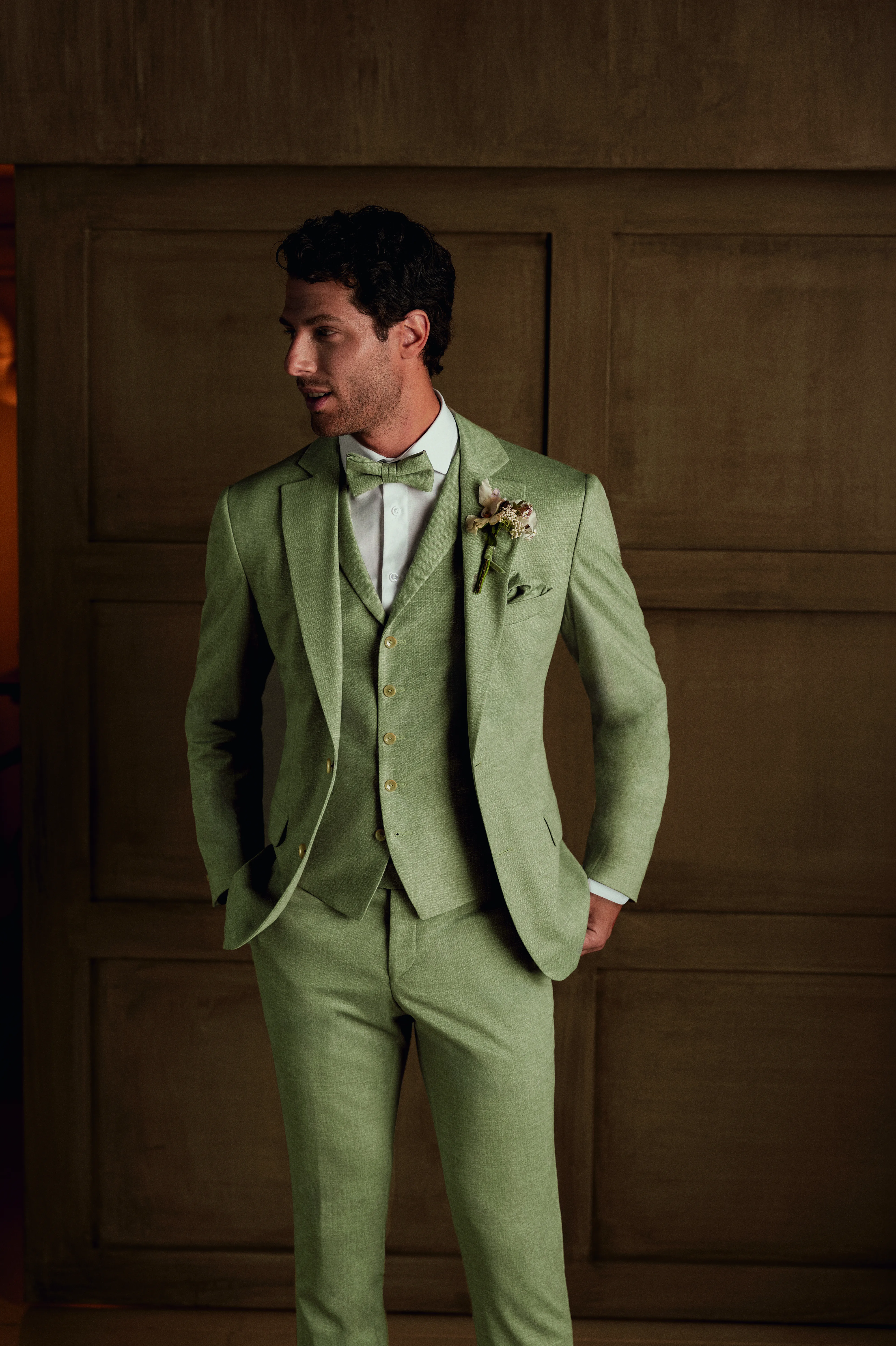 Man poseert in een mooi groen trouwpak.