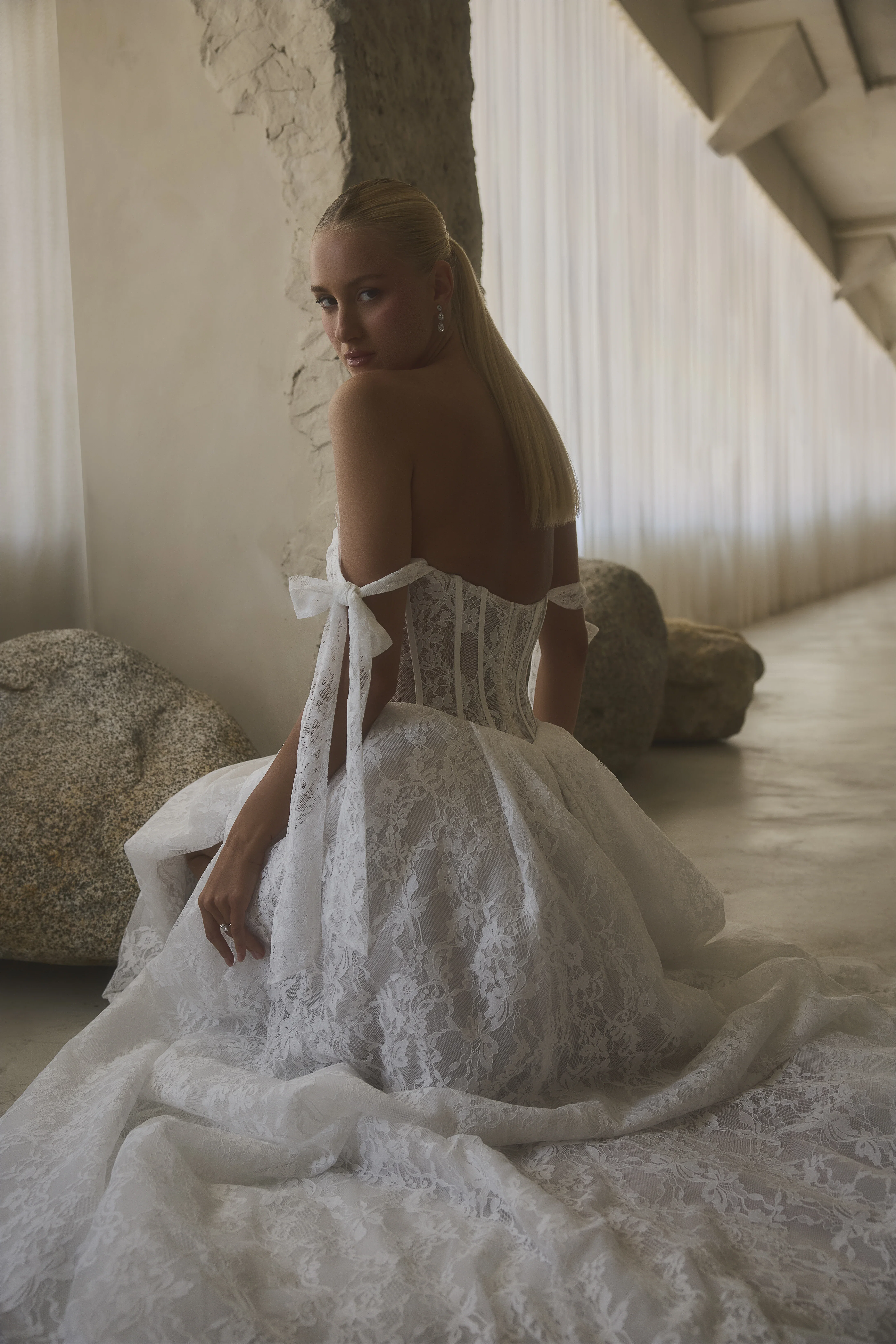 Trouwjurk met strikmouwjtes die half op de bovenarm liggen. De onderkant is van mooi kant.