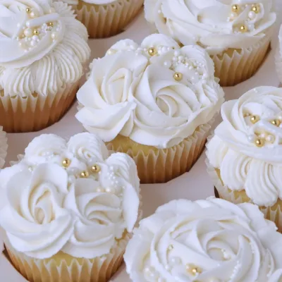 Cupcakes met bruiloftsthema op een witte schaal met bloemenversiering
