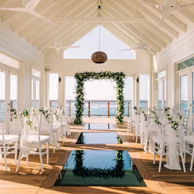 Moderne witte trouwkapel met bloemenboog en uitzicht op de oceaan voor een stijlvolle ceremonie.