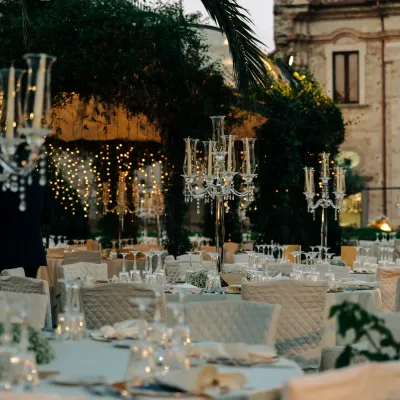 Intiem bruiloftsdiner met lange tafel, bloemen en kaarslicht in avondlicht