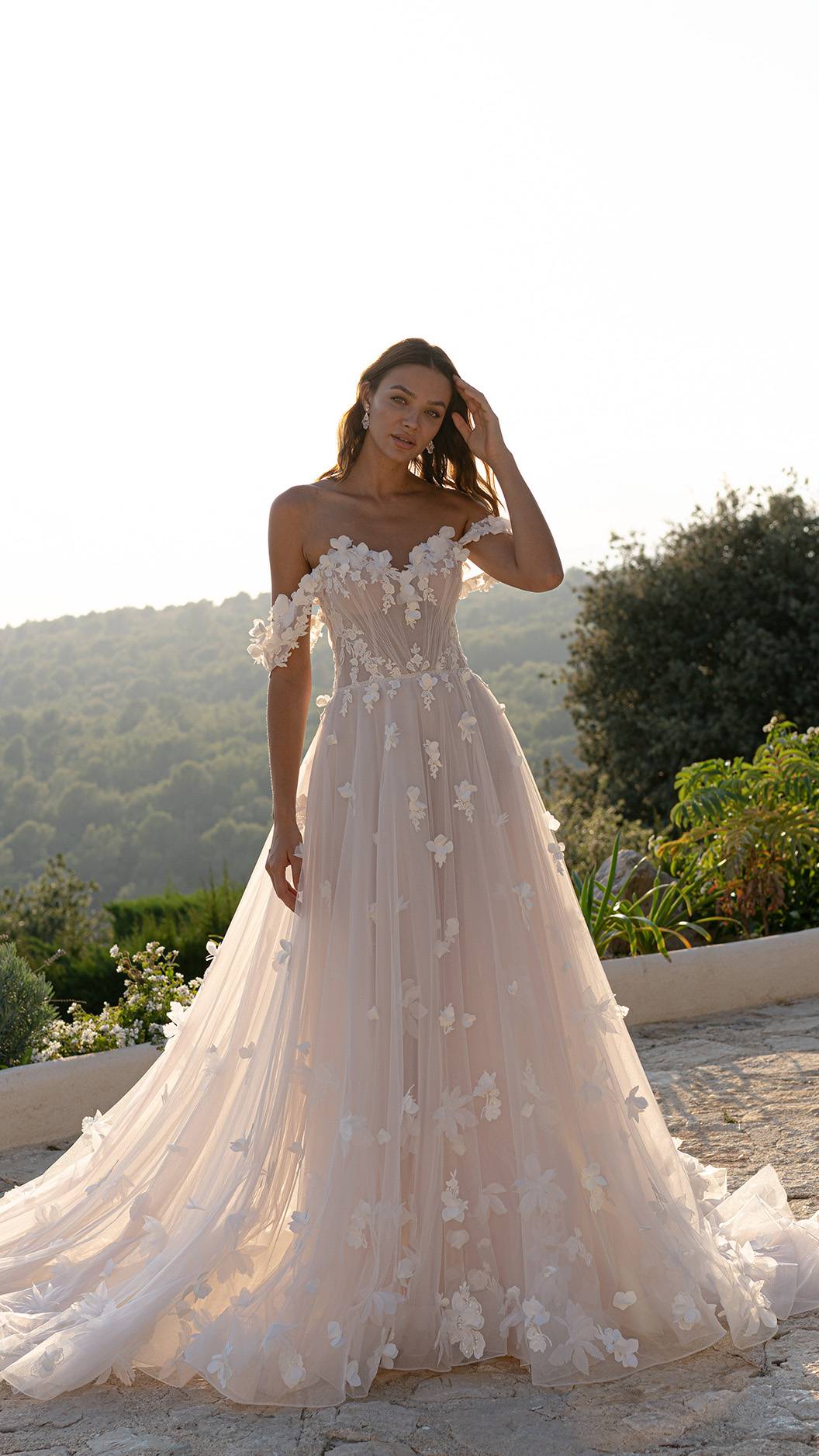 Bruid in Diane Legrand trouwjurk, met sweetheart neckline versierd met bloemen en off-the-shoulder mouwtjes. Mooie tule rok versierd met 3D bloemen.